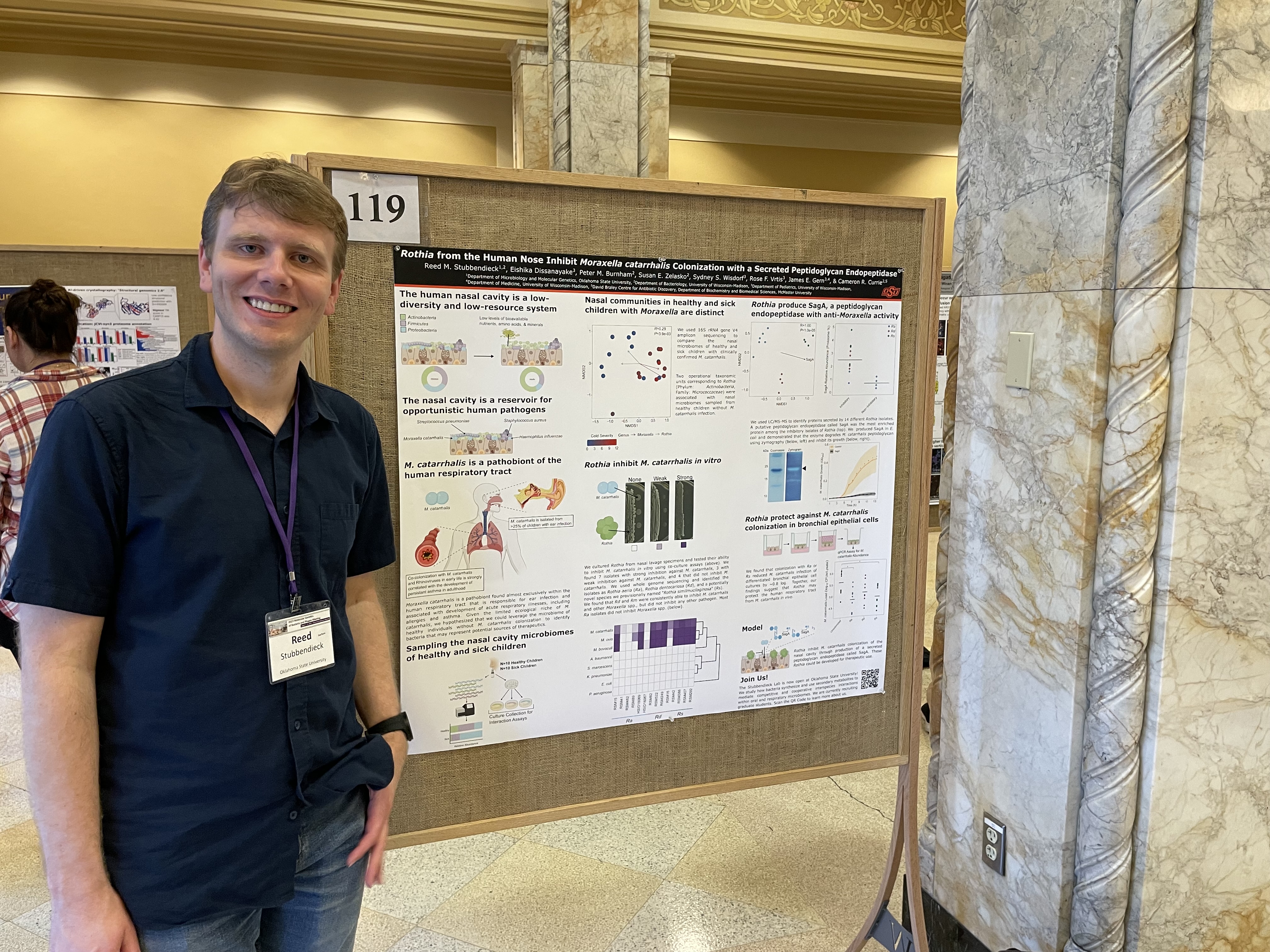 Photograph of Reed standing in front of a poster at the 2023 Phages meeting.